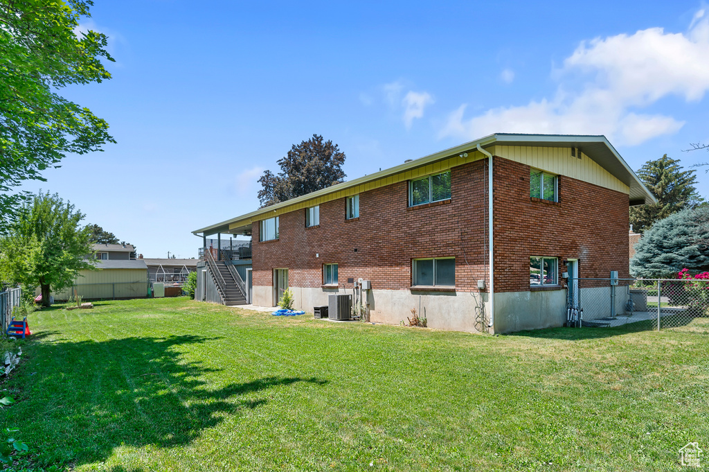 Back of house featuring stairs, a fenced backyard, and brick siding