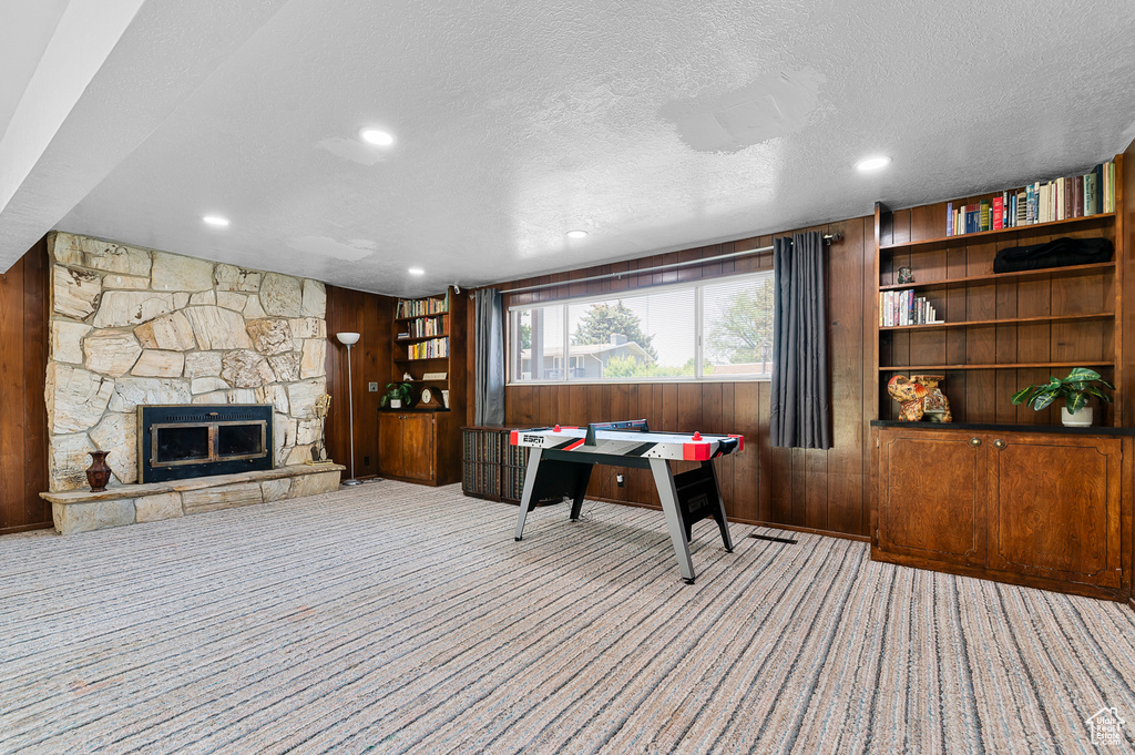 Office space with wood walls, carpet floors, a textured ceiling, a fireplace, and recessed lighting