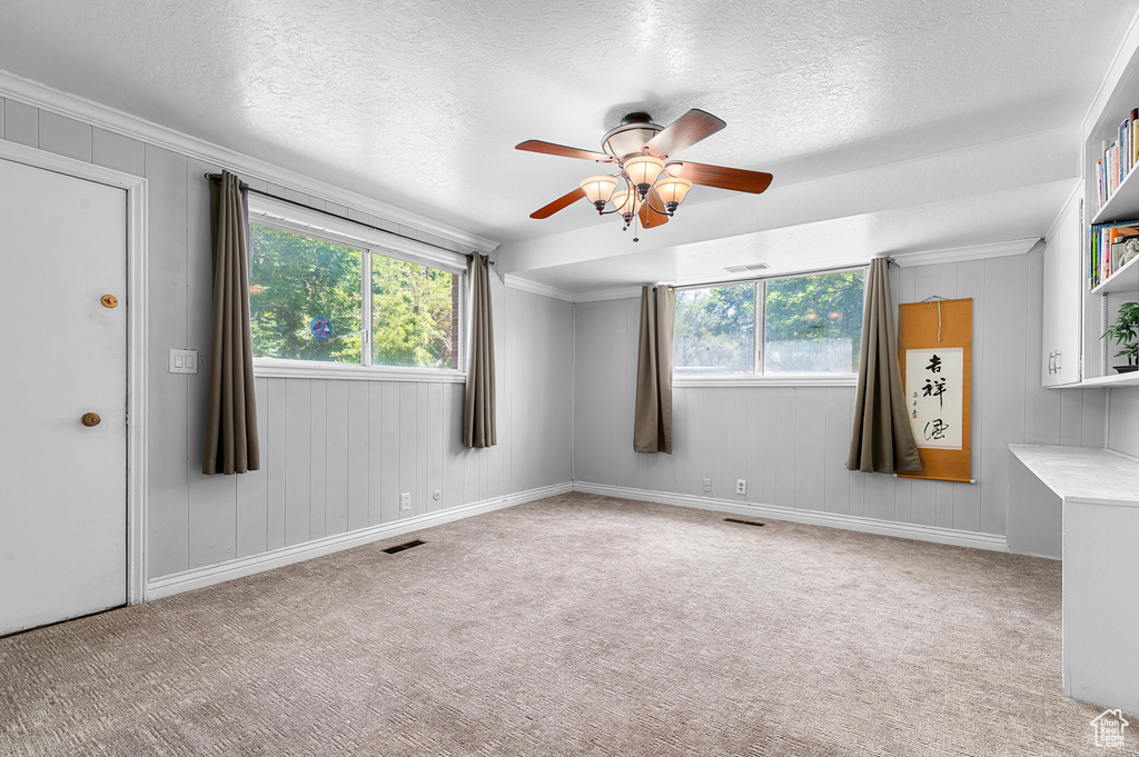 Empty room with ceiling fan, carpet flooring, a textured ceiling, and ornamental molding