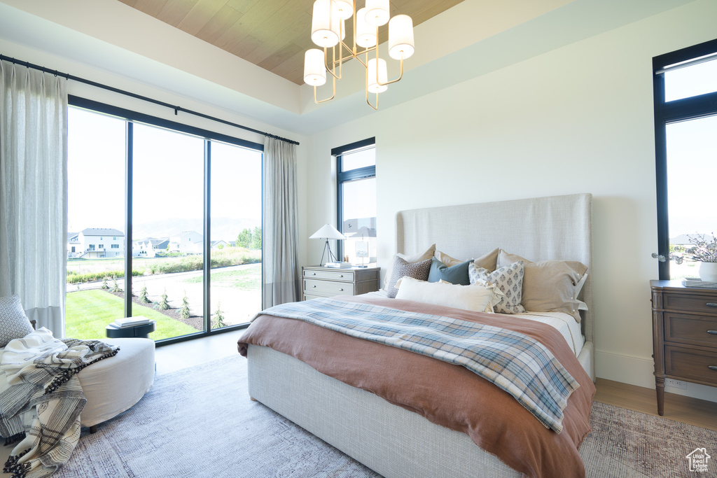 Bedroom with a chandelier, access to exterior, and wood finished floors