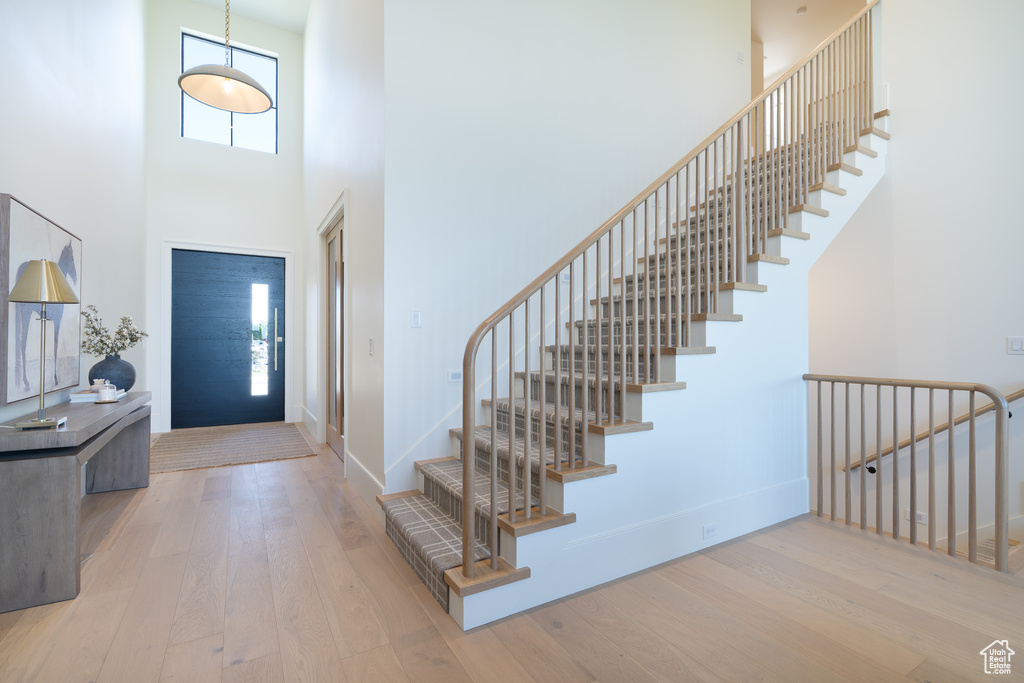 Foyer entrance with hardwood / wood-style floors, a towering ceiling, and stairs