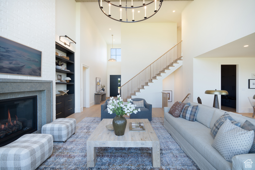 Living area with a high ceiling, built in features, stairway, a glass covered fireplace, and wood finished floors