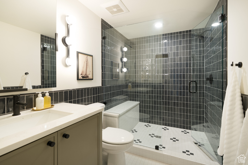 Bathroom featuring vanity, tile walls, a shower stall, and tile patterned flooring