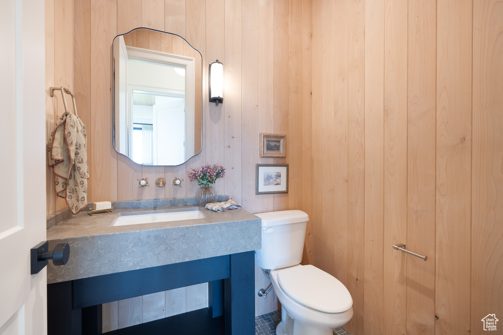 Half bath featuring vanity and wood walls
