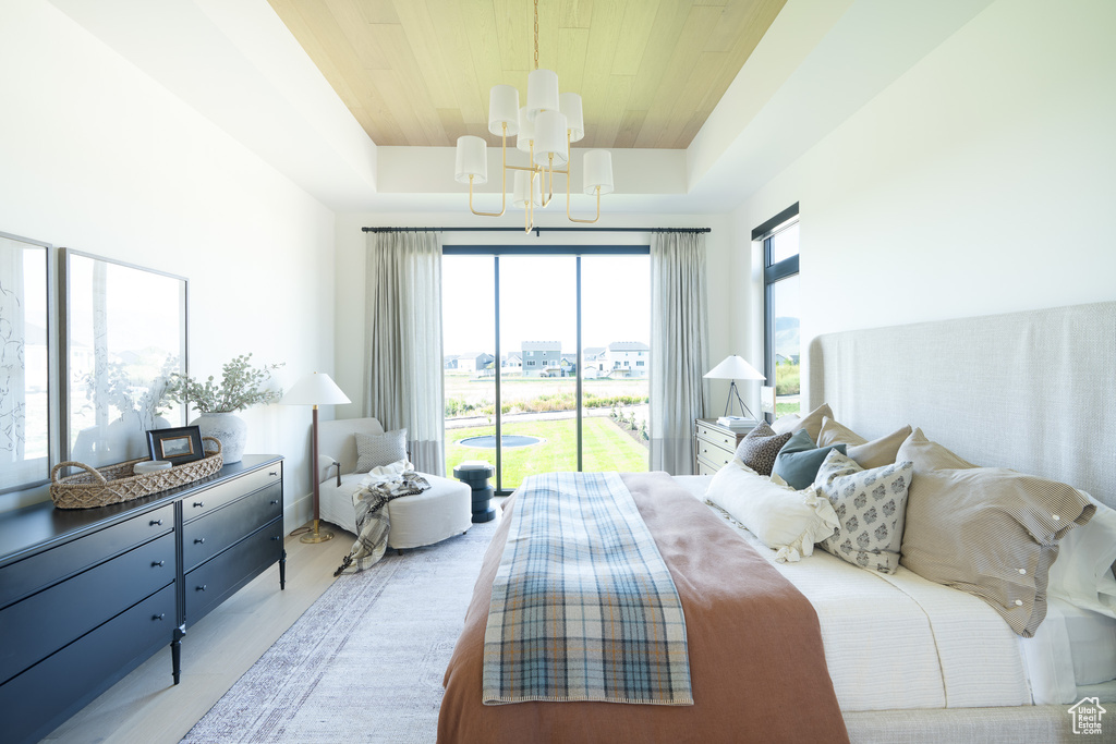 Bedroom with a chandelier, access to exterior, wood finished floors, wooden ceiling, and a raised ceiling