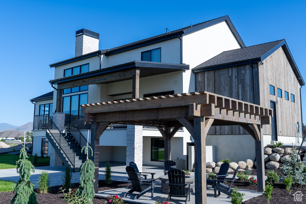 Rear view of property featuring a patio, a chimney, stairs, and a fire pit