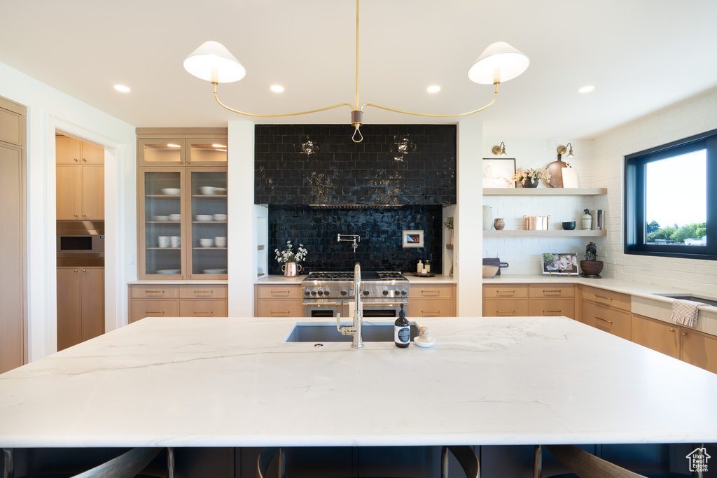 Kitchen with tasteful backsplash, light stone countertops, a kitchen breakfast bar, double oven range, and recessed lighting