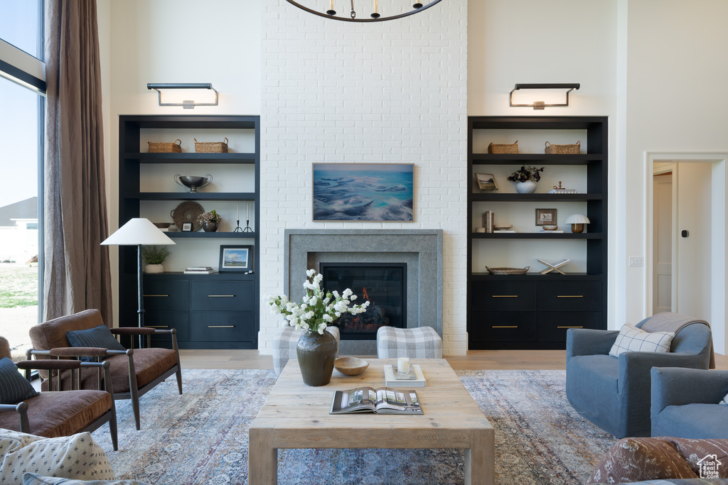 Living room featuring built in features, light wood-style flooring, and a glass covered fireplace