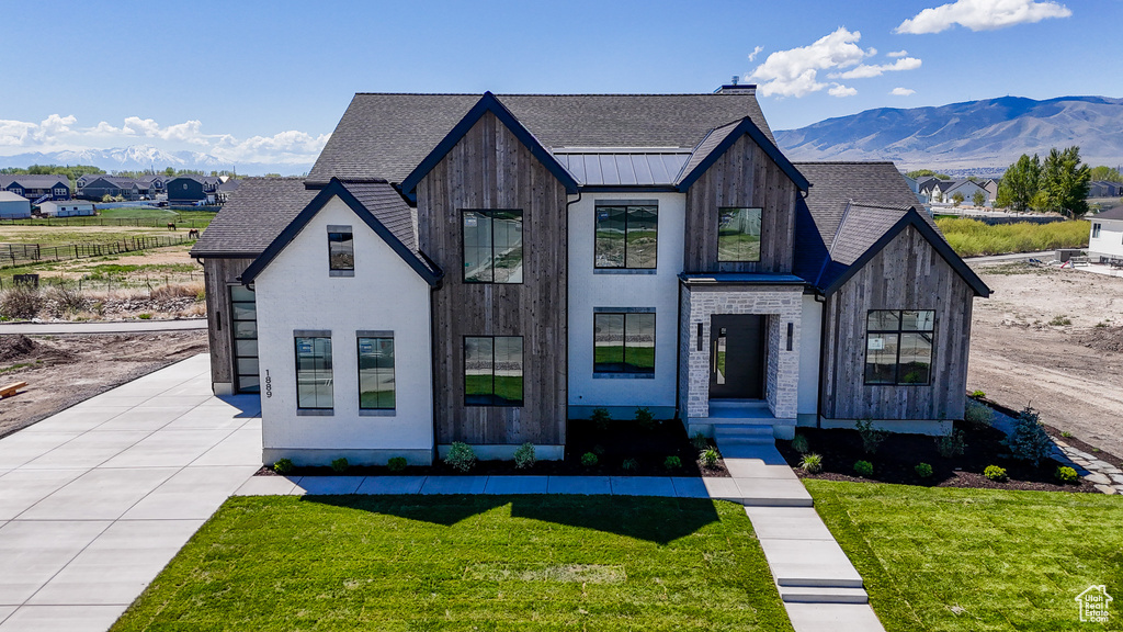 View of front of home featuring a front yard, roof with shingles, and a mountain view