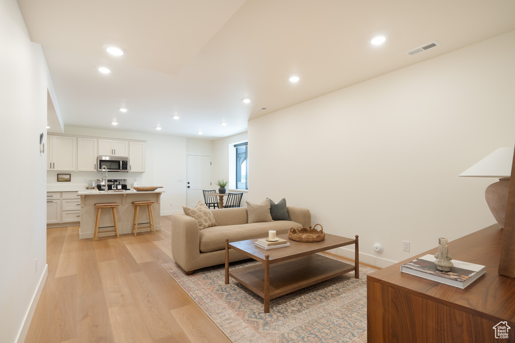 Living area with light wood finished floors and recessed lighting