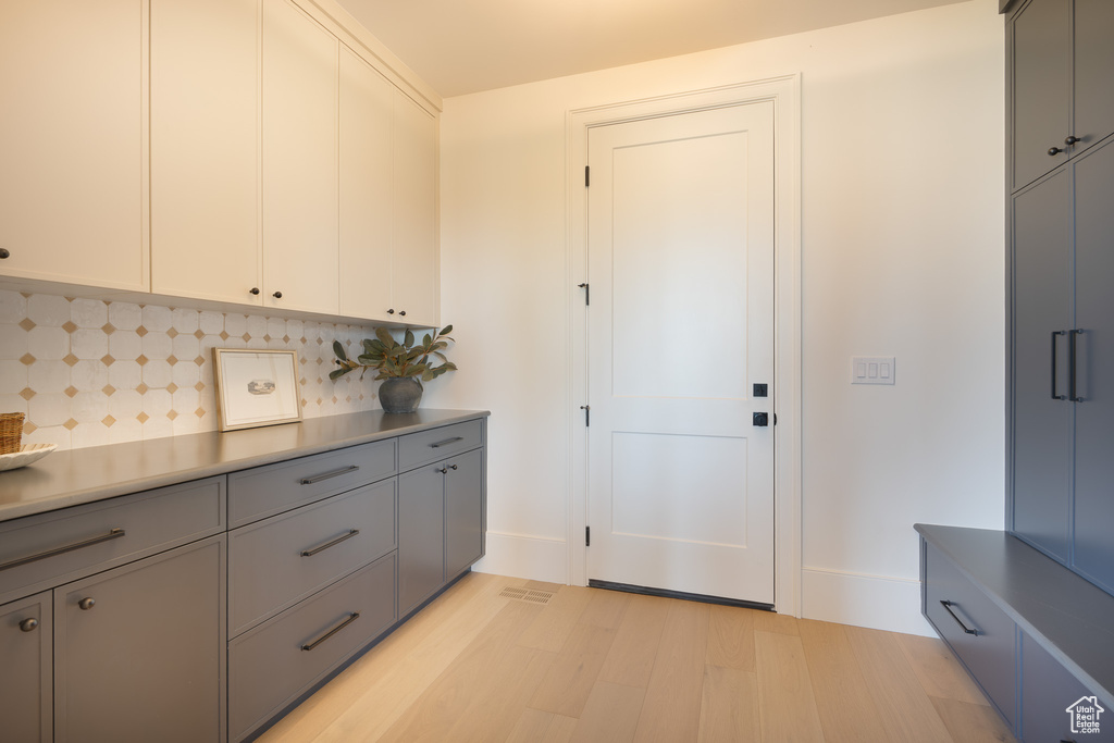 Kitchen with light wood-style flooring, gray cabinetry, and backsplash