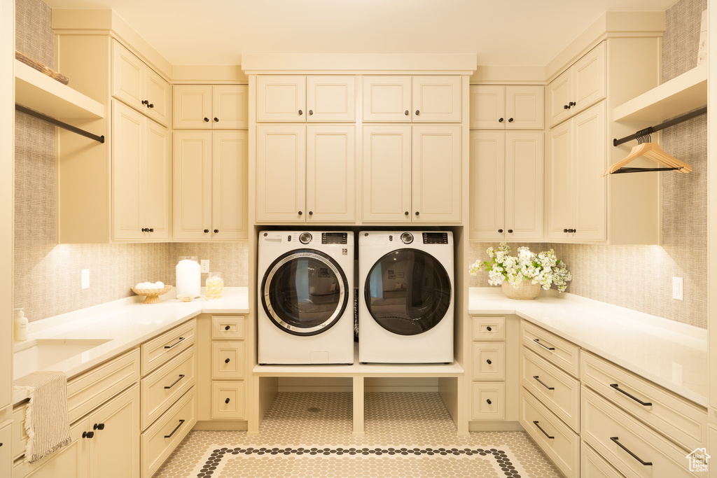 Laundry area with cabinet space, washing machine and dryer, and light tile patterned flooring