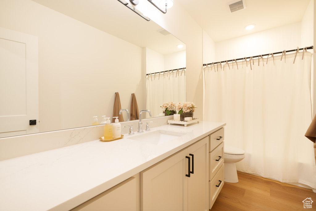 Full bathroom with vanity, wood finished floors, and recessed lighting