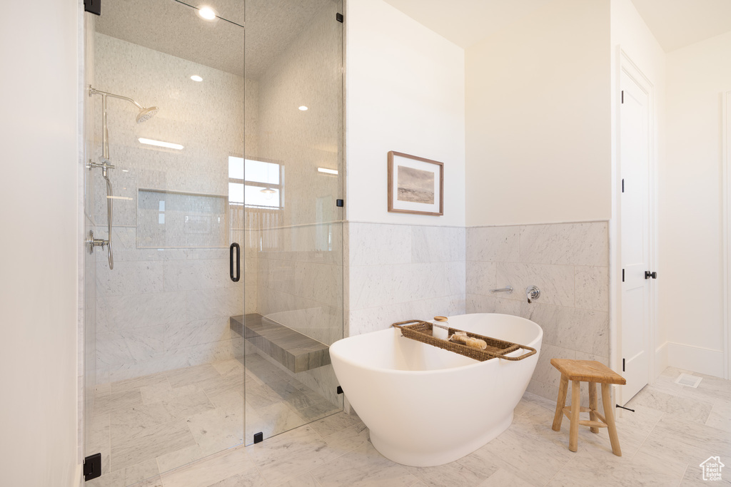 Full bathroom featuring a stall shower, a freestanding bath, marble finish floors, a wainscoted wall, and recessed lighting