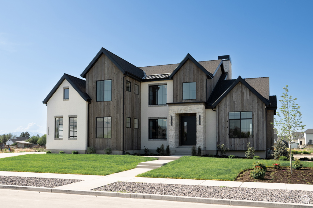 Modern inspired farmhouse with a standing seam roof, a front yard, a metal roof, and a chimney