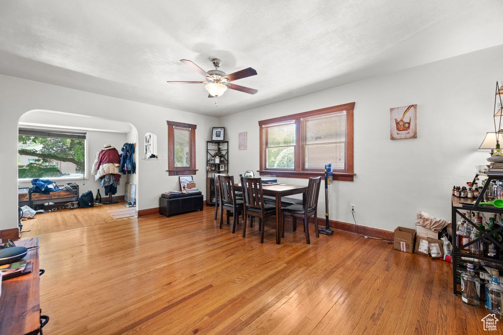 Dining area with a ceiling fan, light wood-style flooring, and arched walkways