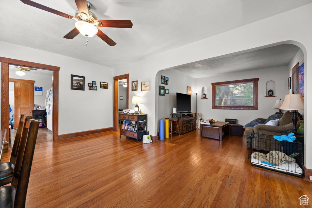 Living area featuring a ceiling fan, arched walkways, and wood finished floors