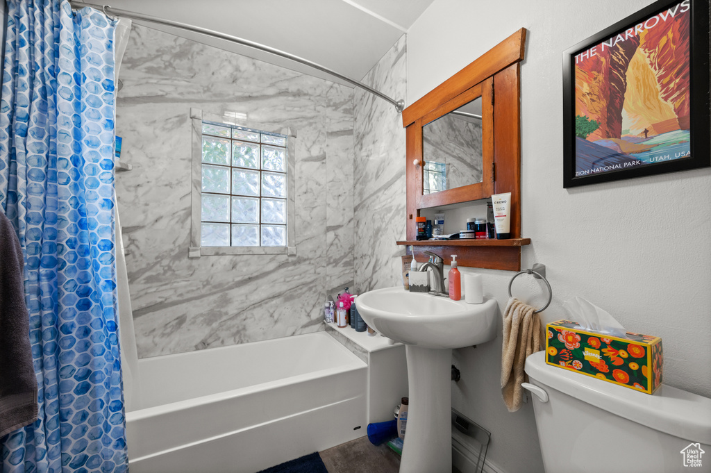 Bathroom featuring toilet and shower / tub combo with curtain