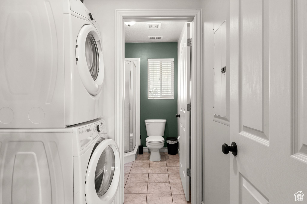 Laundry room featuring stacked washer / drying machine and light tile patterned floors