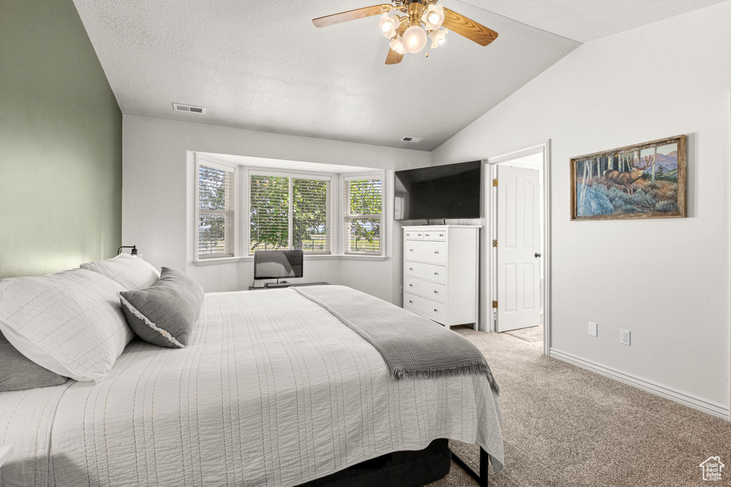 Bedroom featuring light colored carpet, lofted ceiling, and a ceiling fan
