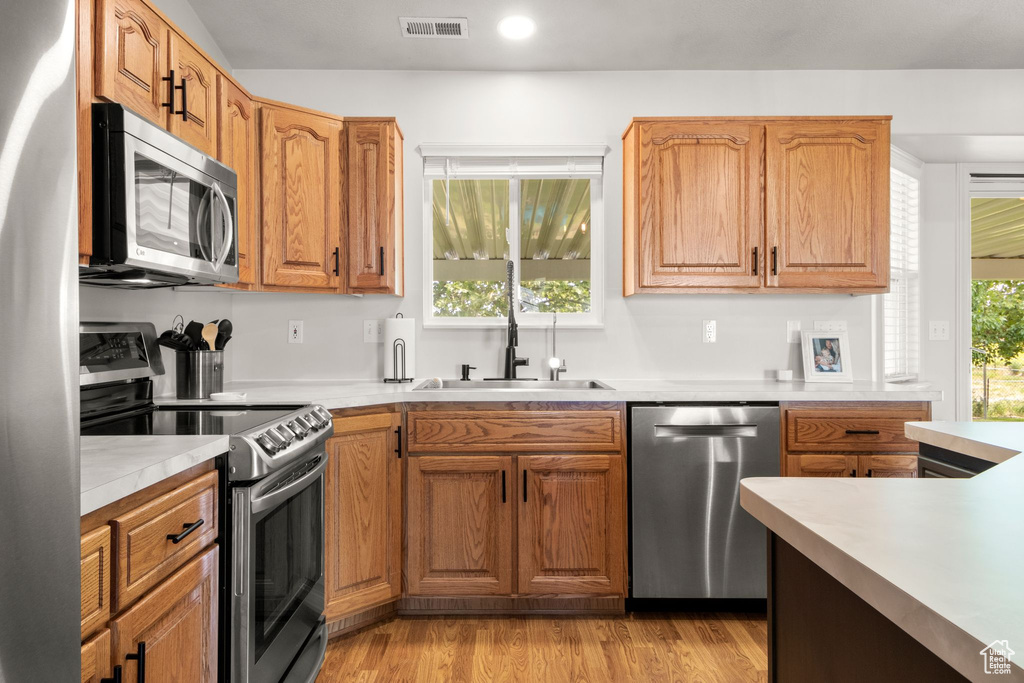 Kitchen with appliances with stainless steel finishes, light countertops, light wood-type flooring, recessed lighting, and brown cabinetry