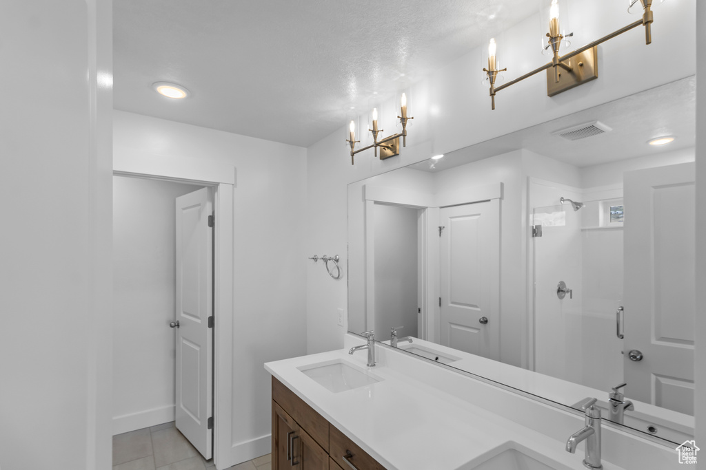 Bathroom with double vanity, a stall shower, tile patterned floors, recessed lighting, and a chandelier