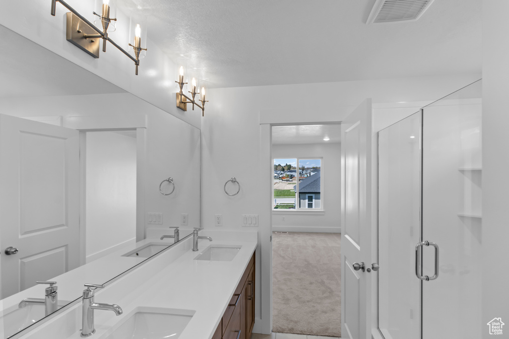 Bathroom featuring double vanity, a stall shower, and a chandelier