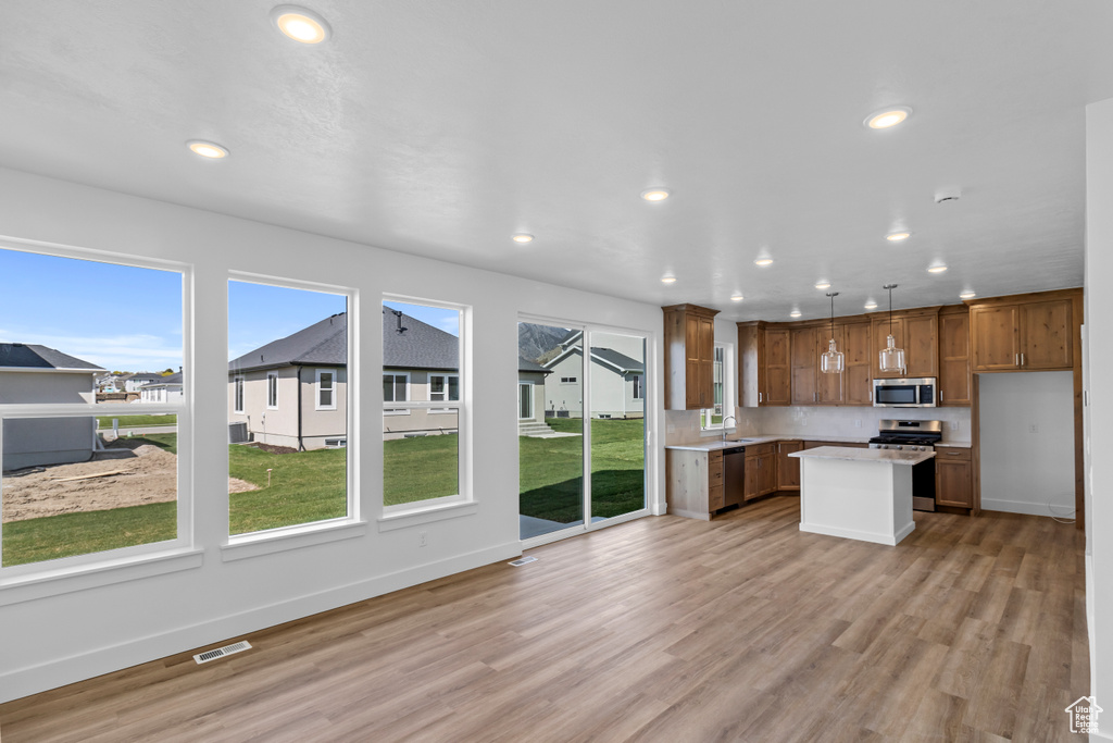 Kitchen with appliances with stainless steel finishes, recessed lighting, light countertops, light wood-type flooring, and a center island