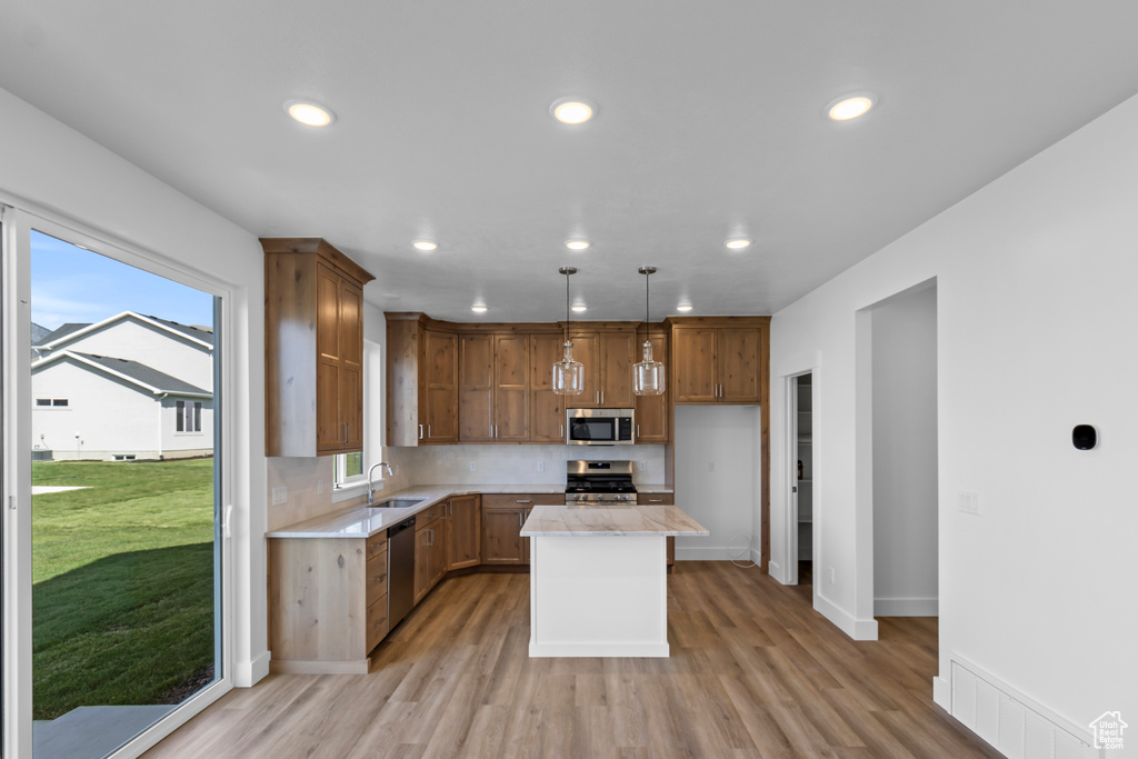 Kitchen with appliances with stainless steel finishes, light countertops, recessed lighting, light wood finished floors, and decorative backsplash
