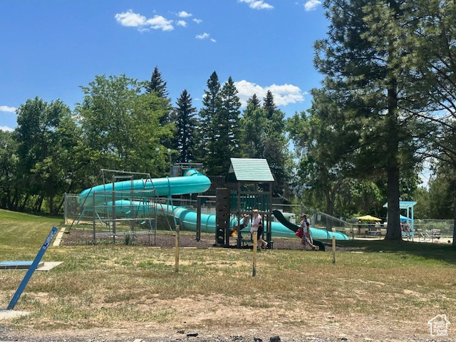 Communal playground with a lawn and view of wooded area