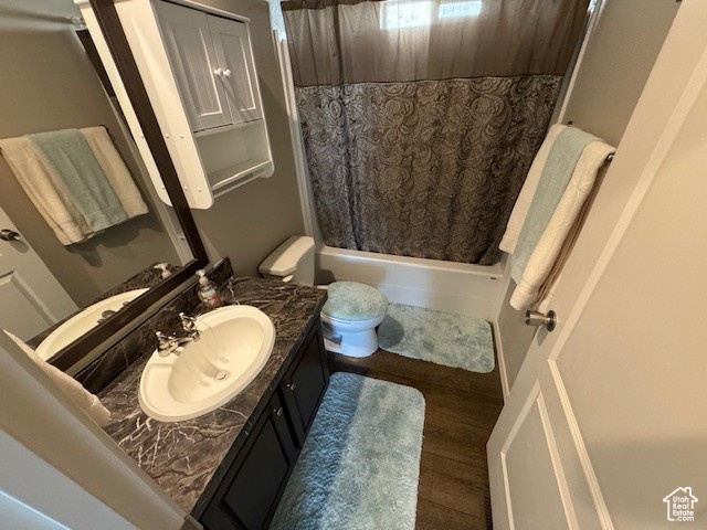 Full bathroom with vanity, shower / bath combo, and wood finished floors