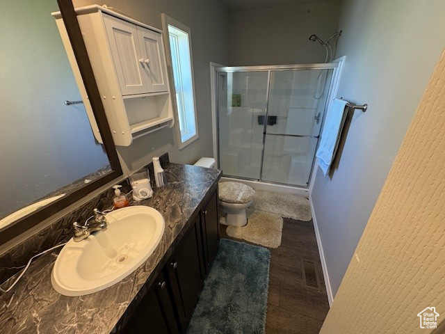 Bathroom featuring a stall shower, vanity, and wood finished floors