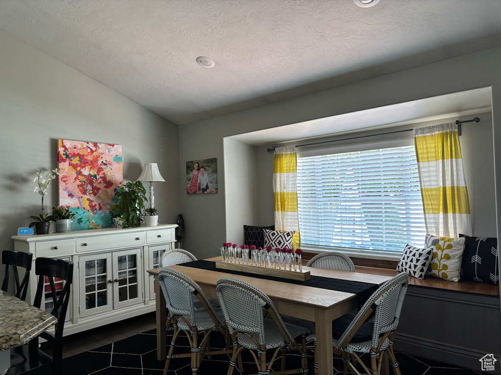 Dining area featuring vaulted ceiling, a textured ceiling, and dark tile patterned flooring