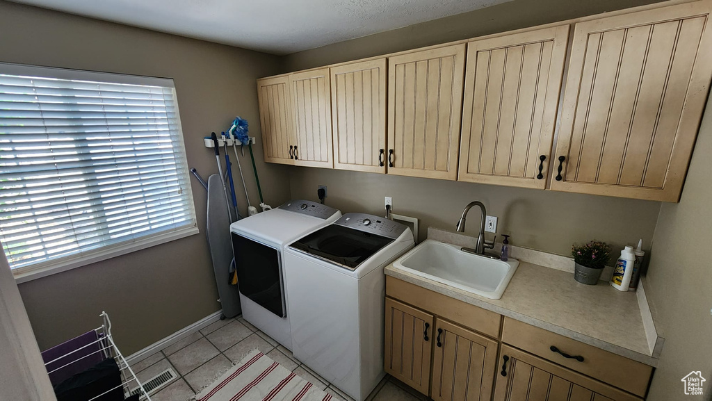 Laundry room featuring washing machine and dryer, cabinet space, and light tile patterned flooring