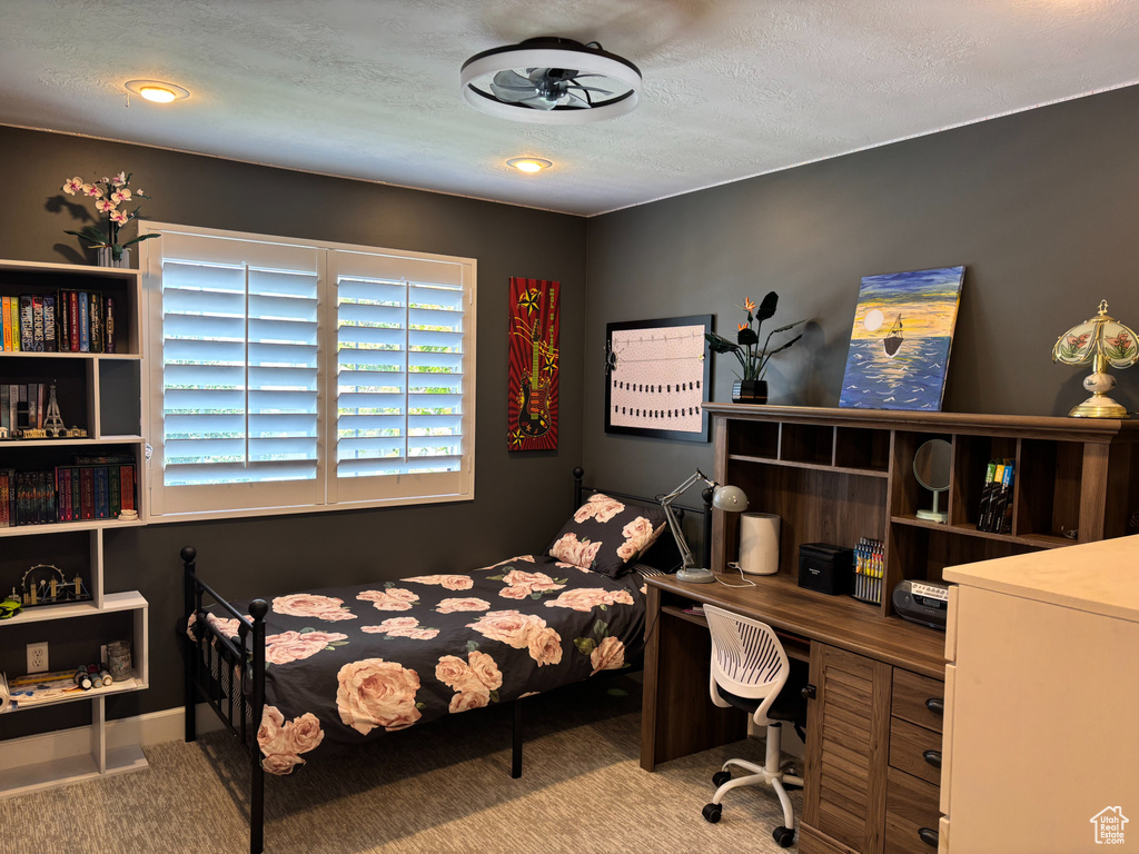 Carpeted bedroom with a textured ceiling and a desk