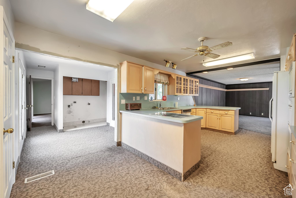 Kitchen with a peninsula, light brown cabinetry, light carpet, and a ceiling fan