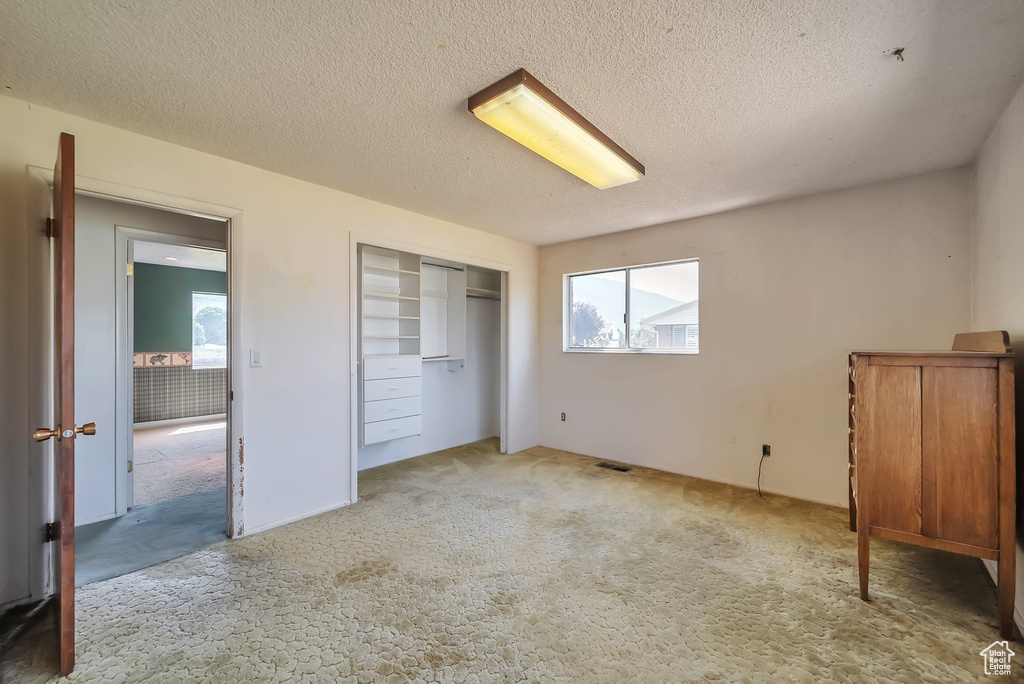 Unfurnished bedroom featuring carpet, a textured ceiling, and a closet