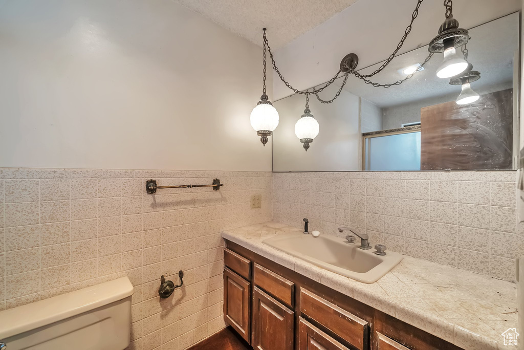 Full bathroom featuring vanity, tile walls, wainscoting, and a shower with door
