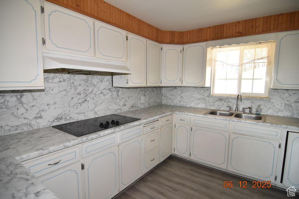 Kitchen featuring black electric cooktop, under cabinet range hood, decorative backsplash, light countertops, and white cabinets