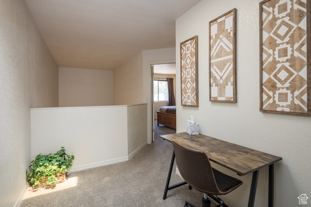 Office space featuring carpet and a textured wall