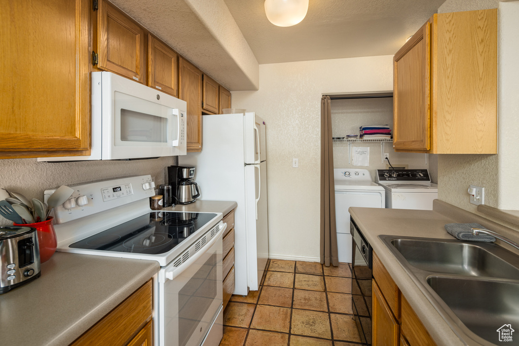 Kitchen with washer and clothes dryer, white appliances, brown cabinets, and light countertops
