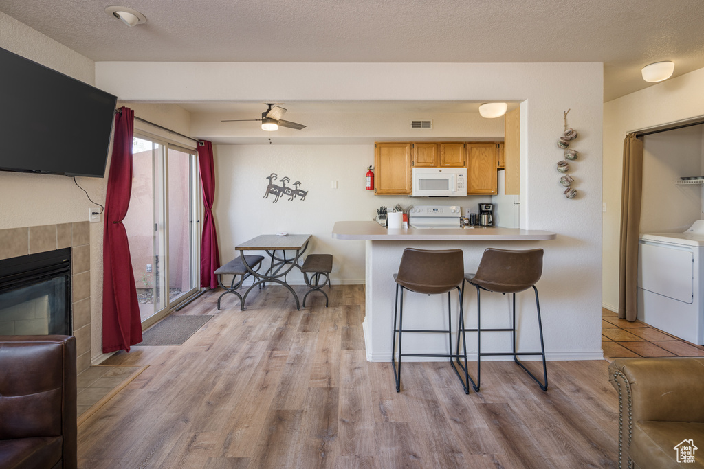 Kitchen featuring white appliances, washer / dryer, a kitchen breakfast bar, and light wood-style flooring