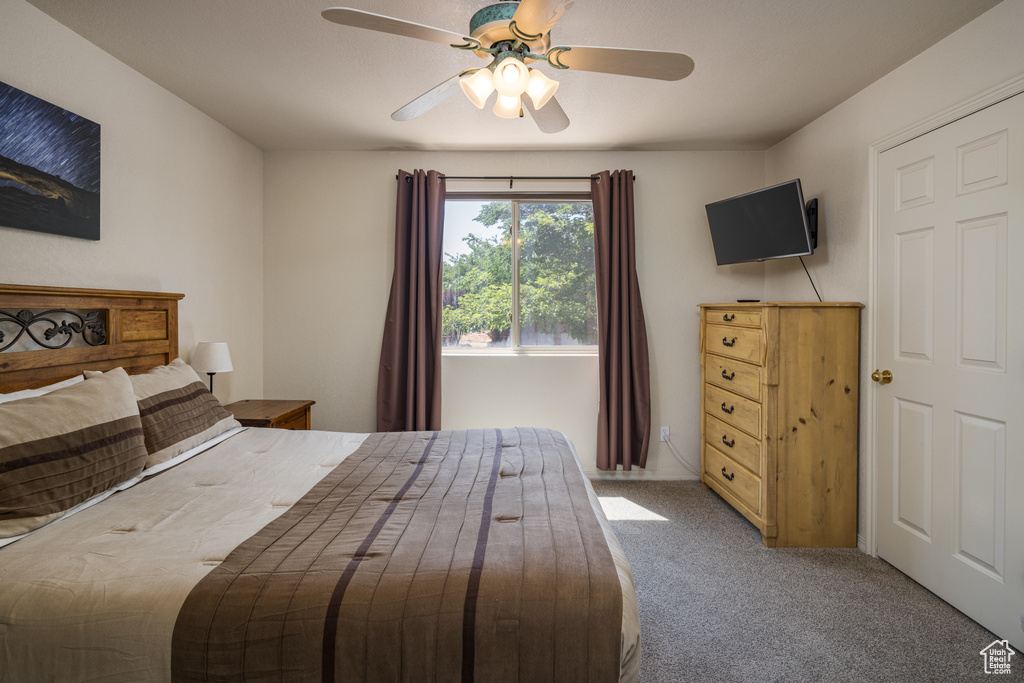 Carpeted bedroom with a ceiling fan