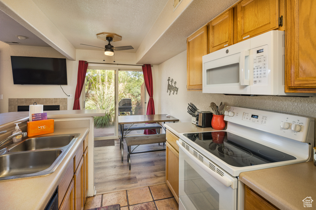 Kitchen with white appliances, a ceiling fan, light countertops, and a textured ceiling