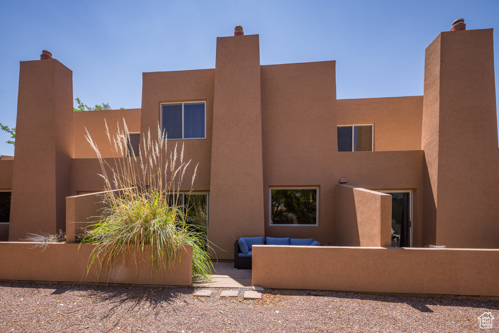 Back of house with stucco siding and outdoor lounge area