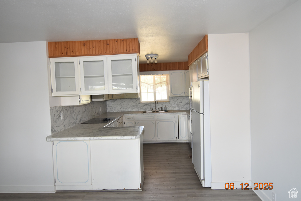 Kitchen featuring black electric stovetop, a peninsula, freestanding refrigerator, and light countertops