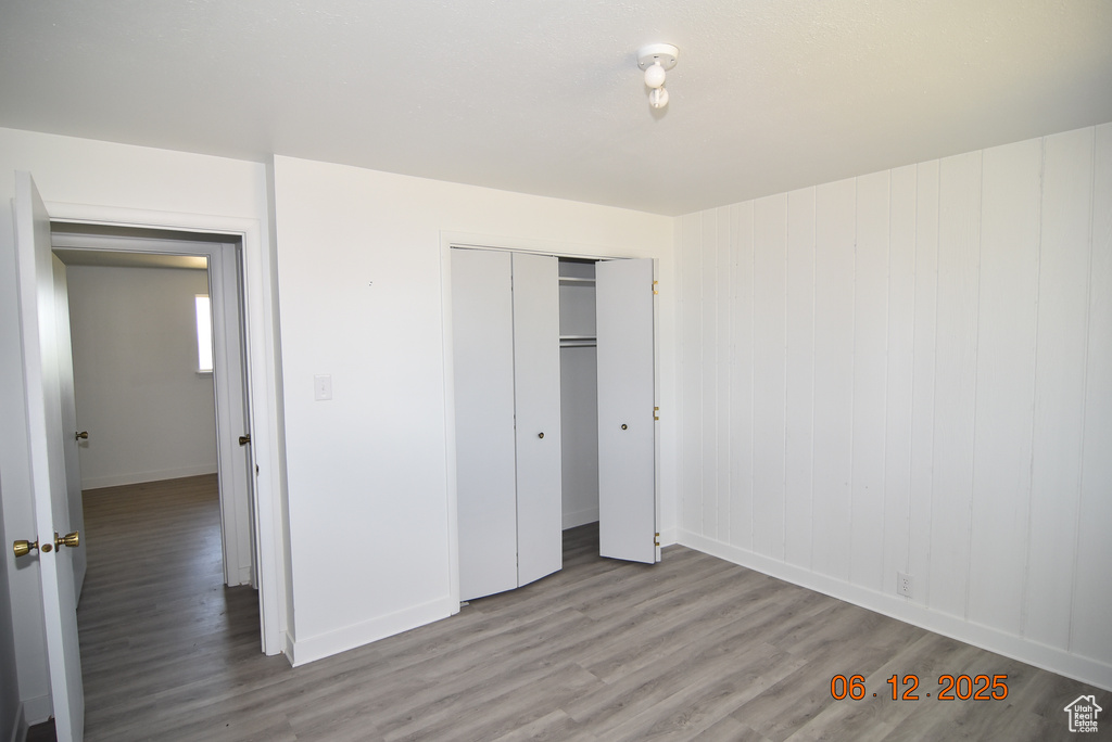 Unfurnished bedroom with wood finished floors and a closet