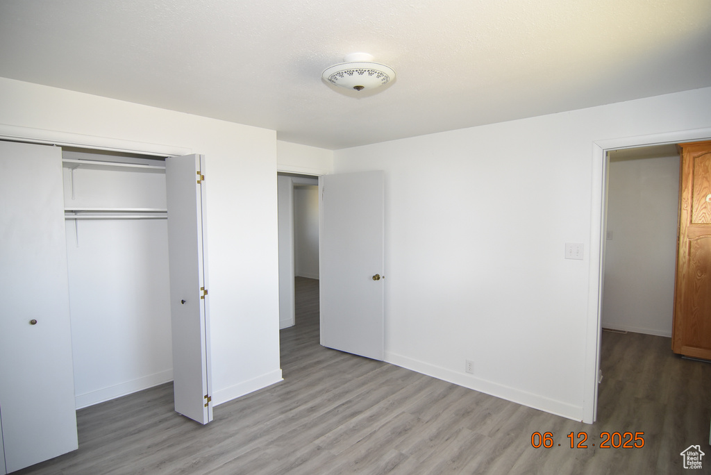 Unfurnished bedroom with wood finished floors and a closet