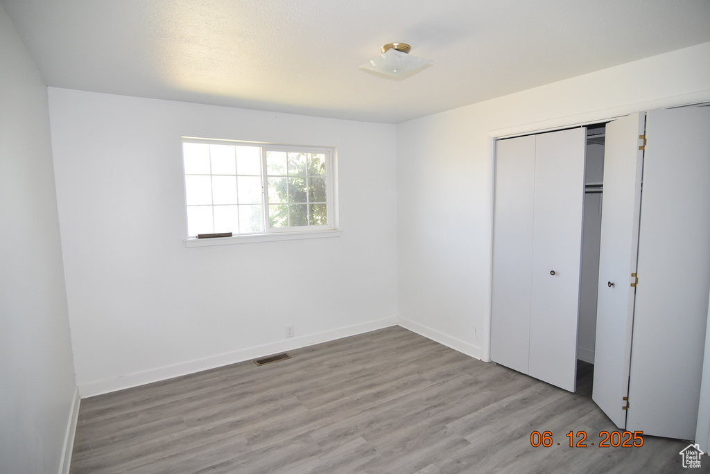 Unfurnished bedroom with wood finished floors and a closet