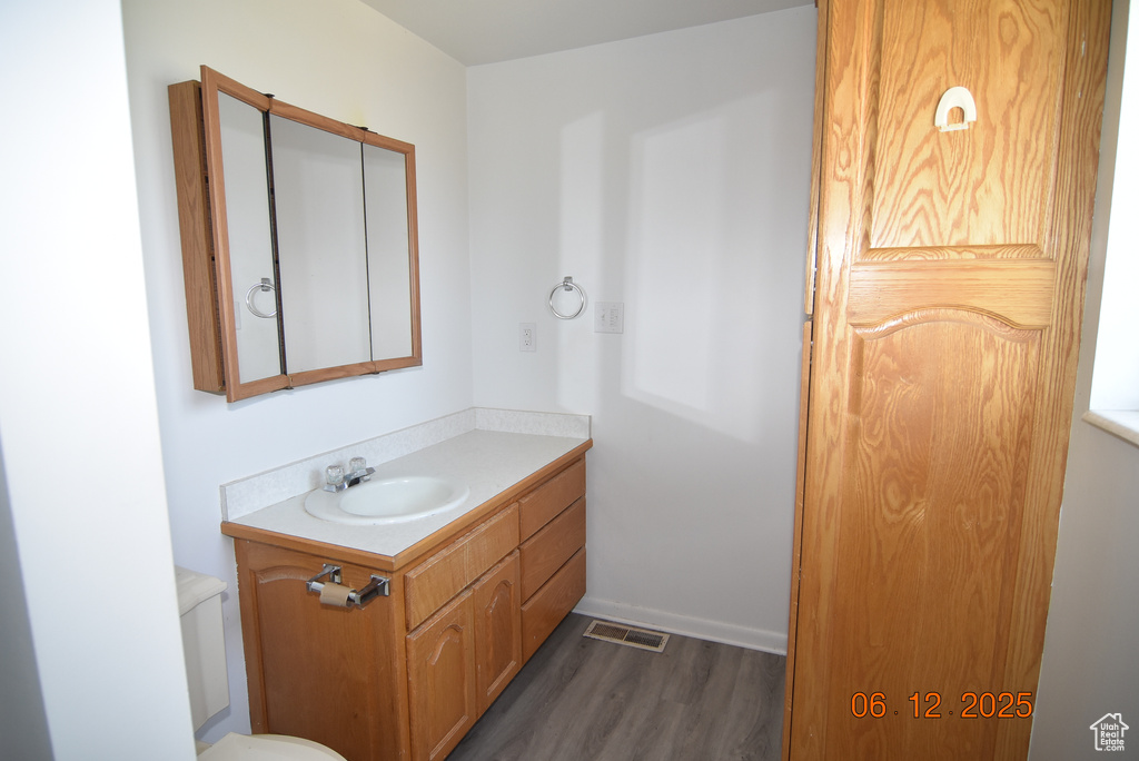 Half bath with wood finished floors and vanity